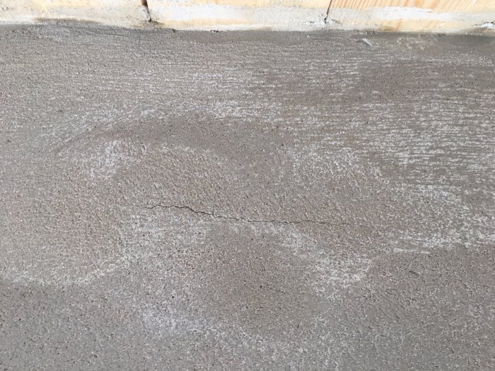 Närbild på en nyligen putsad vägg med sprickor och ränder i putsen.