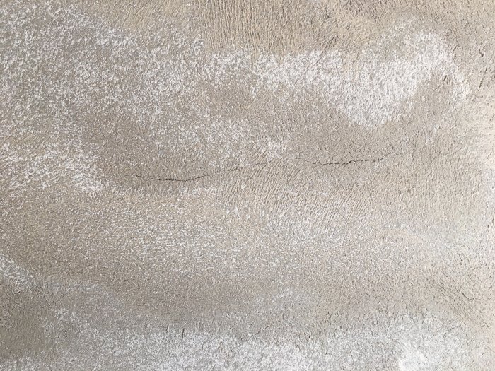 Nyputsad grå vägg med synliga sprickor och ojämn textur på Finja Isoblock.