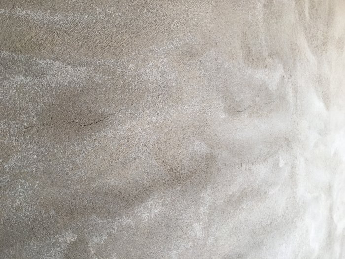 En nyligen putsad vägg med sprickor och ojämnheter på ytan.