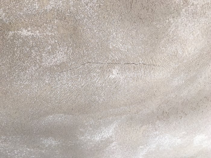 Spricka i nyputsad grå vägg av Finja Isoblock med synliga ränder i putsen.