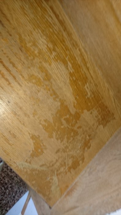 Trappa före renovering med gammal lack som slits bort under slipningsprocessen.