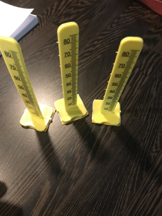 Gula avståndshållare för golv på ett mörkt underlag.
