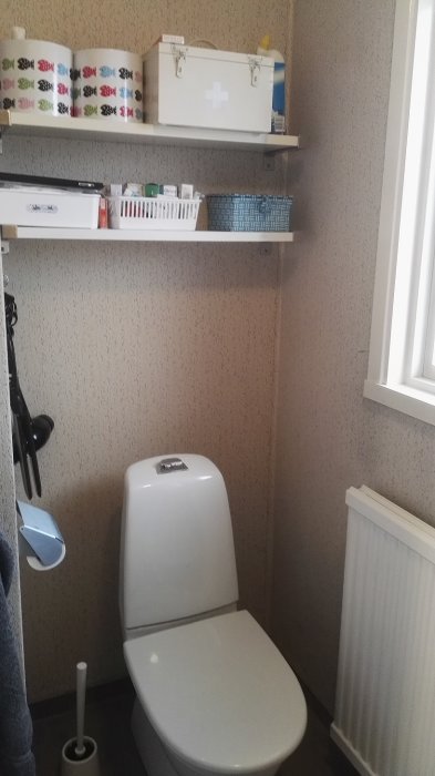 Renoverat badrum från 1973 med ny WC-stol, strukturtapet, radiator och förvaringshyllor.