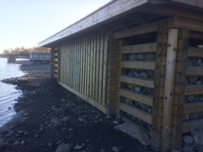 Nybyggt vågskydd i trä med 45*145 plankor och förankring med armeringsjärn vid vattenkanten.