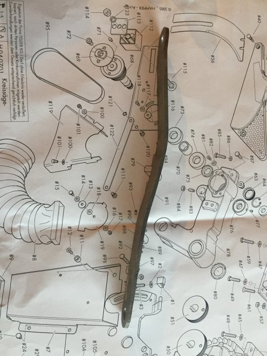 Böjd metallkomponent på en sprängskiss för maskindelar, indikerande möjlig deformation.