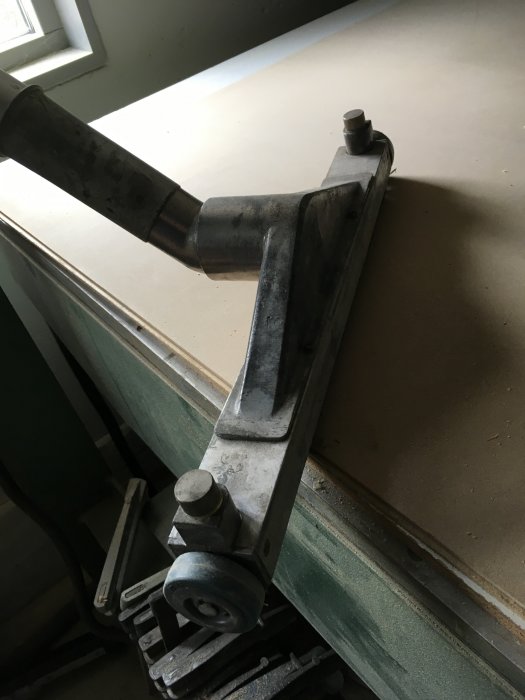 Metalldel med Ergo-handtag monterat, placerat på en verkstadsbänk, och relaterat till mottaget paket med golvmunstycken.