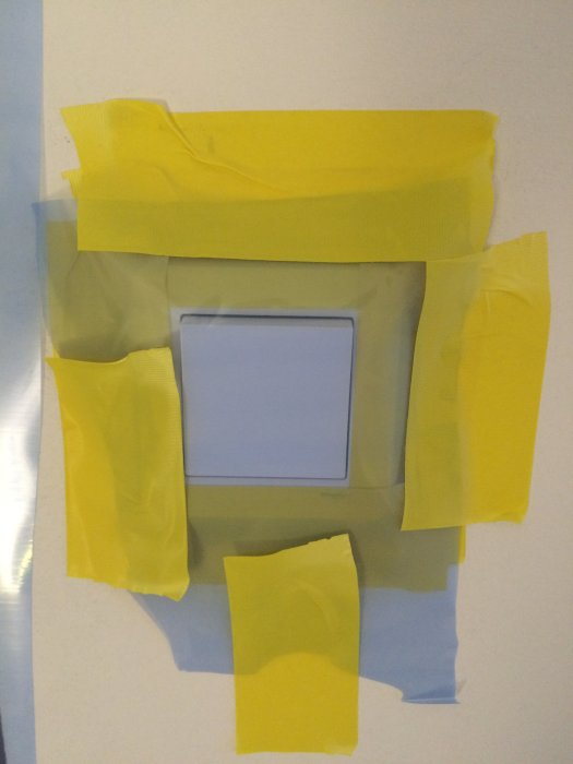 En väggströmbrytare maskerad med gult tejp för målning.
