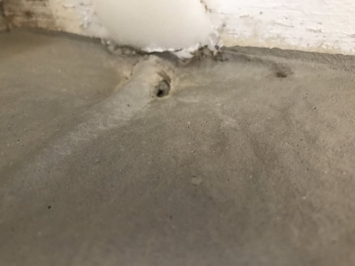 Flytspackel nära en vägg under ett element, med en synlig fördjupning i spacklet.