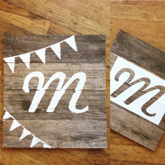Två träskyltar med vita bokstäver "m" och vimplar på träbakgrund.