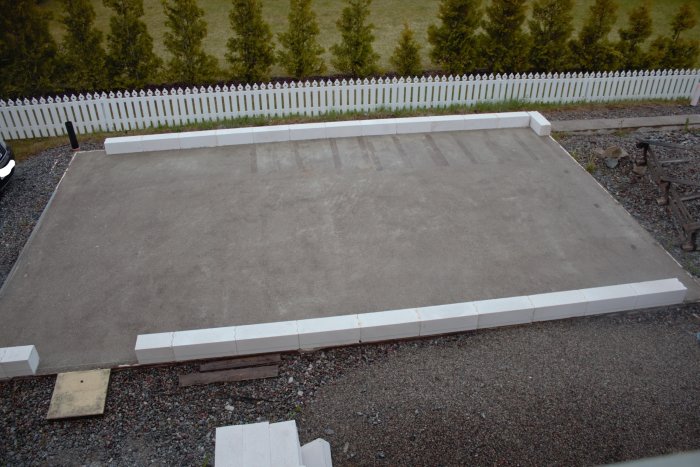 Betongplatta med nyligen påbörjad konstruktion av lättbetongblock längs kanten.