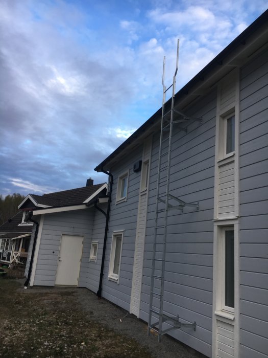 Nymålat grått hus med uppskruvad stege på sidan och garage med insatt port.