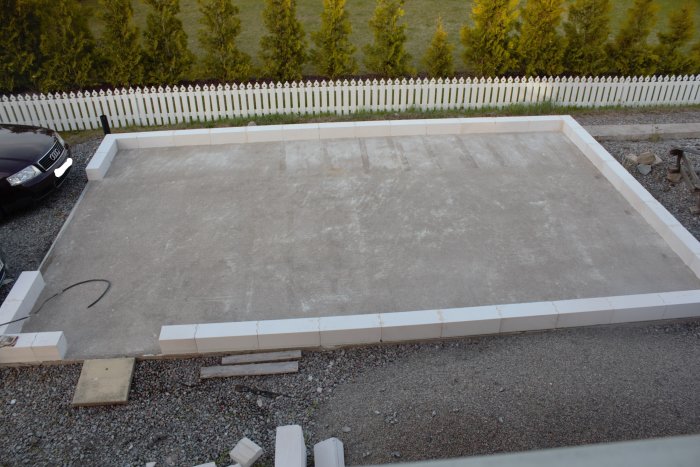 Nylagd betongplatta med vita grundmurar för ett byggprojekt, torrt väder.