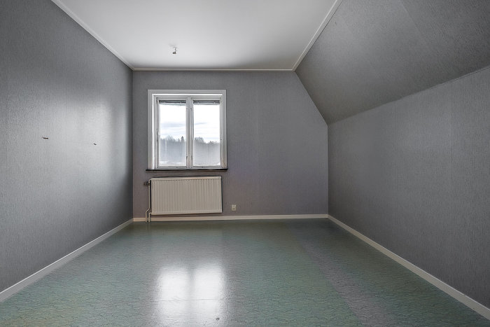 Tomt rum med nytapetserade väggar och osmyckade golv före taklistar och lister installeras.