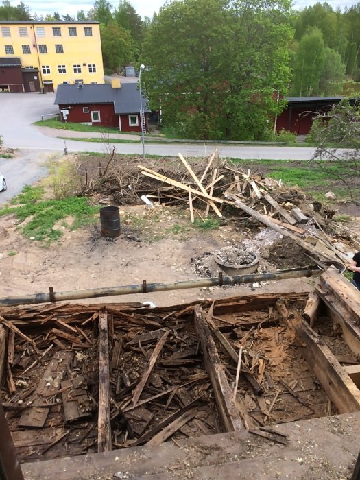 Rivningsarbete av en farstukvist med synliga övre stolpar och en hög med gammalt virke.