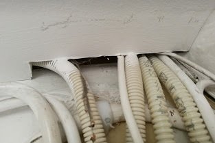 Genomföring av kablar i vägg med synligt hål och tecken på vitmögel.