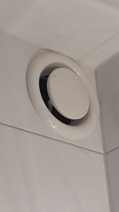 Vit kontrollventil monterad på kakelvägg i badrum som borde vara en frånluftsventil enligt OVK-besiktningen.