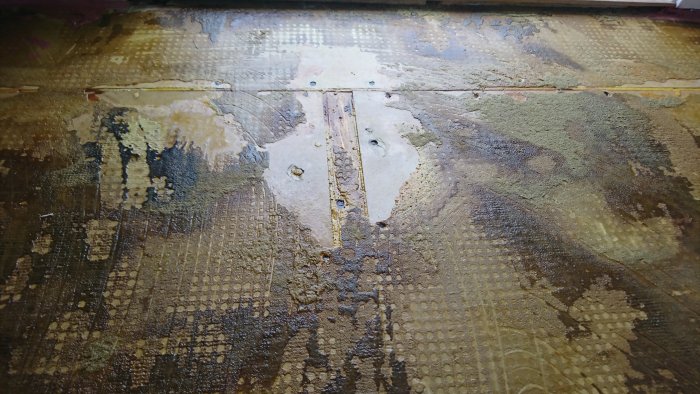 Ojämnt undergolv med rester av gammal mattlim och avtryck, behov av avjämning innan nytt golv läggs.