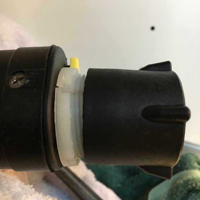 Närbild på potentiellt trasig koppling mellan blandare och diskmaskin med sneda gängor.