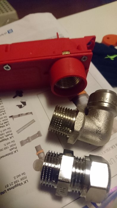 VVS-kopplingar från LK på arbetsbord, inklusive röd box och instruktioner.