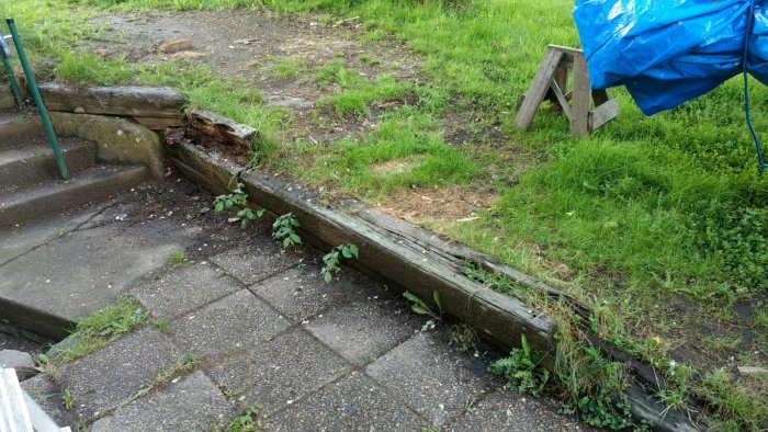 Ruttnande slipersmur som håller upp en slänt bredvid en trappstegsinfart.