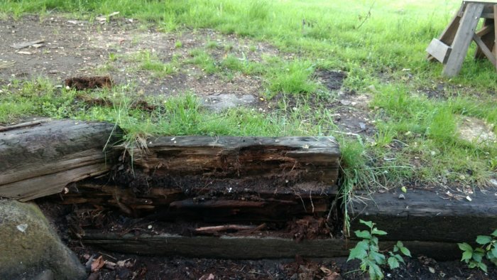 Ruttnande slipersmur som håller upp slänt, med synligt berg och vegetation.