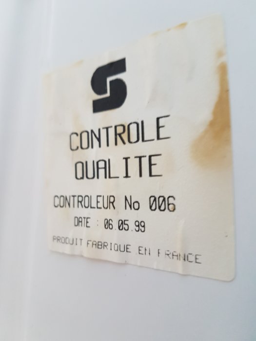 Etikett märkt "CONTROLE QUALITE" med fläckar, datum "06.05.99" och "FABRIQUE EN FRANCE".