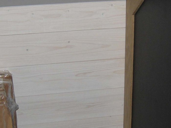 Råspontpanel 120x28 mm, träfjädern osynlig efter installation, nära vägg i hörn.
