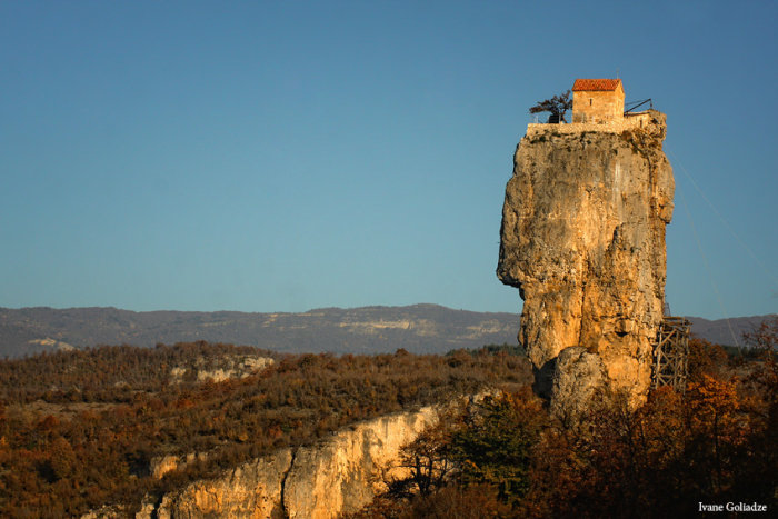 Enstaka stenpelare med ett ensamt hus på toppen i ett bergslandskap.