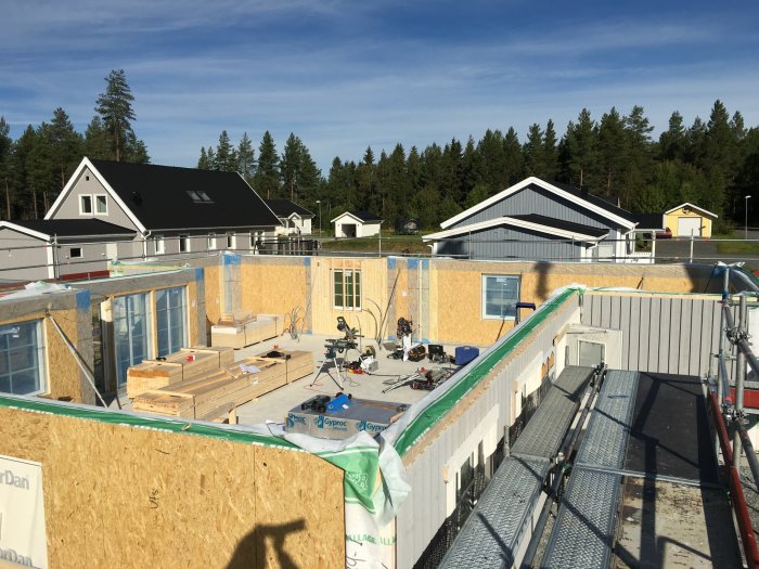 Stomresning av hus med synliga träväggar, fönsterpartier och byggmaterial på dagen.