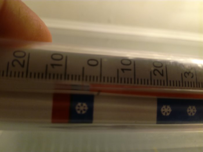 Termostatinställning i kylskåp visar cirka +3 grader Celsius och delvis suddig bild.