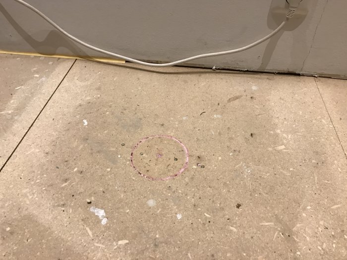 Ett utmärkt område på ett bjälklag där ett hål planeras att sågas för isolering med lösull nära en yttervägg.