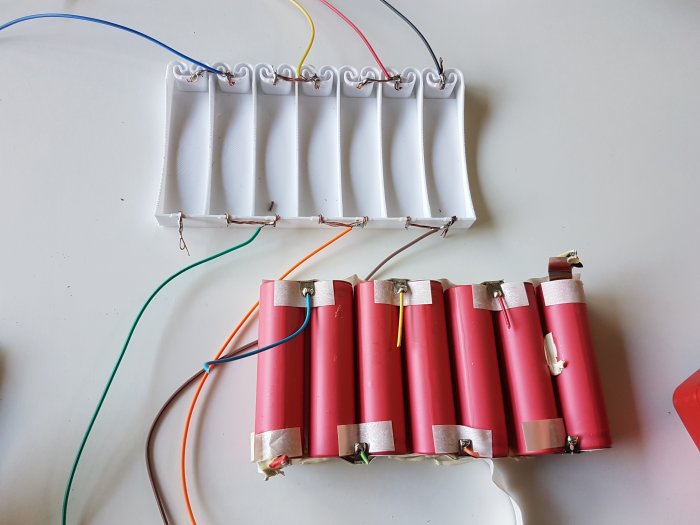 Batteripack med röda 18650-celler och en 3D-utskriven hållare med ledningar och kontakter.