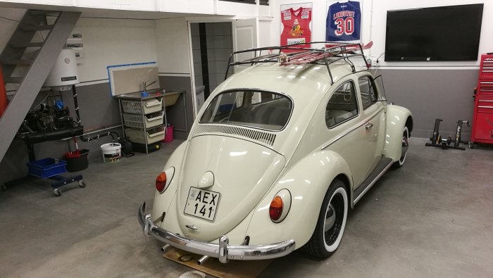 Renoverad Volkswagen Bubbla i ett rent, organiserat garage med verktyg och en TV på väggen.