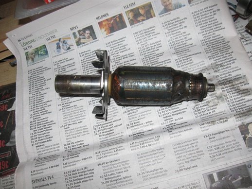 Borrmotorankare med nytt lager och fläktkåpa på en tidning, synliga brandmärken och slitage på motorn.
