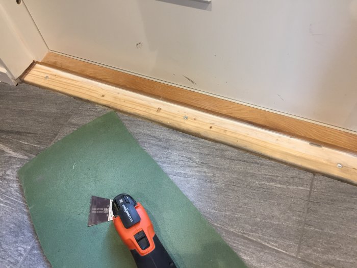 Ej färdiginstallerad trätröskel vid dörröppning med verktyg och arbetsmaterial nära.