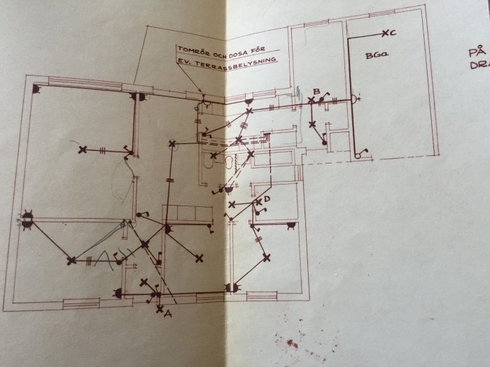 Handritad elinstallationsplan för ett hus med markeringar för elcentral, vägguttag och belysning.