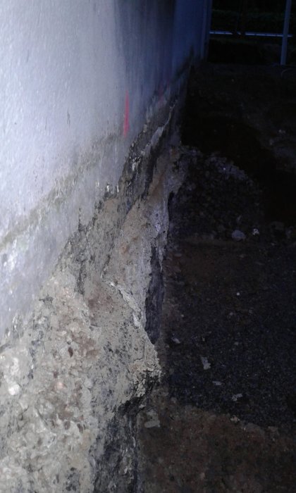 Ojämn källarvägg nära utgrävd mark inför tillbyggnad och isolering.