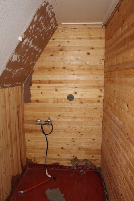 Badrum under renovering med träväggar, synliga rör och avslitet tak.
