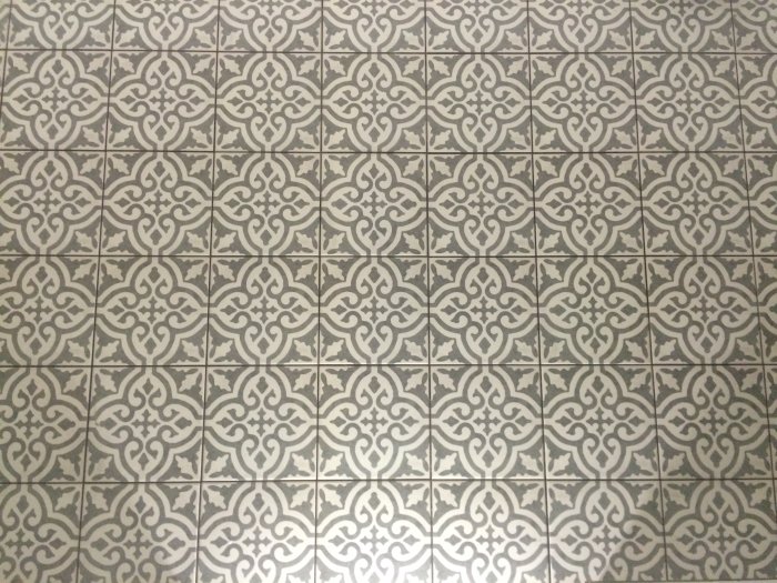 Mattkaklat golv med symmetriskt, dekorativt mönster i grått och vitt.