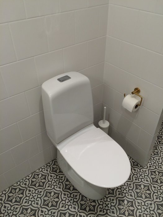 Renoverat badrum med Ifö Spira toalett utan spolkant, mässingsdetaljer och mönstrat golv.