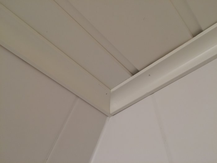Renoverad hörna med vita taklister och kakelvägg, snygg finish utan synliga kablar.