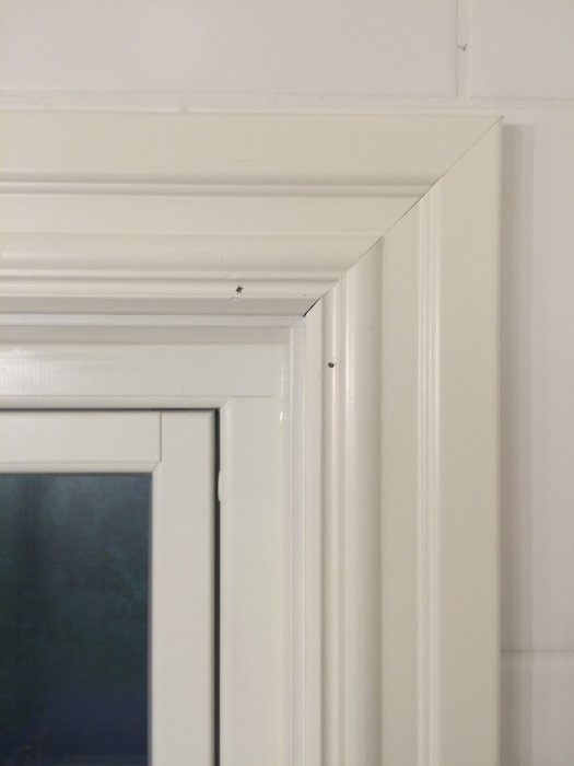 Välgjort hörn av vitmålad dörrkarm och listverk med en spegelreflektion.