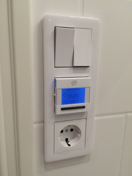 Väggmonterad ljusstyrningspanel med termostatdisplay och strömuttag.