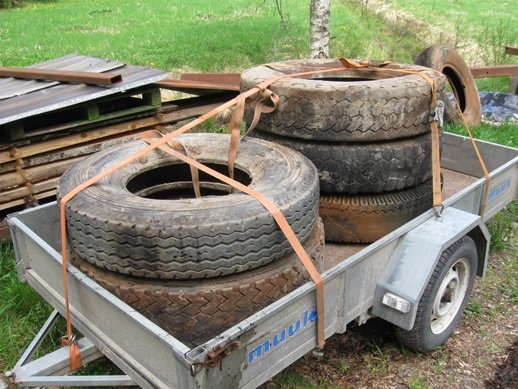 Lastat släp med flera gamla däck och skrot redo att transporteras för återvinning.