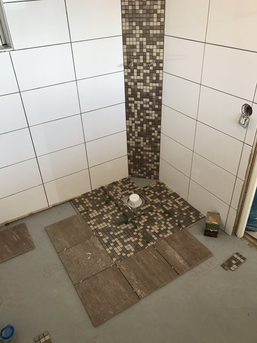 Utlagd mosaik och klinkers i pågående arbete med badrumsrenovering.