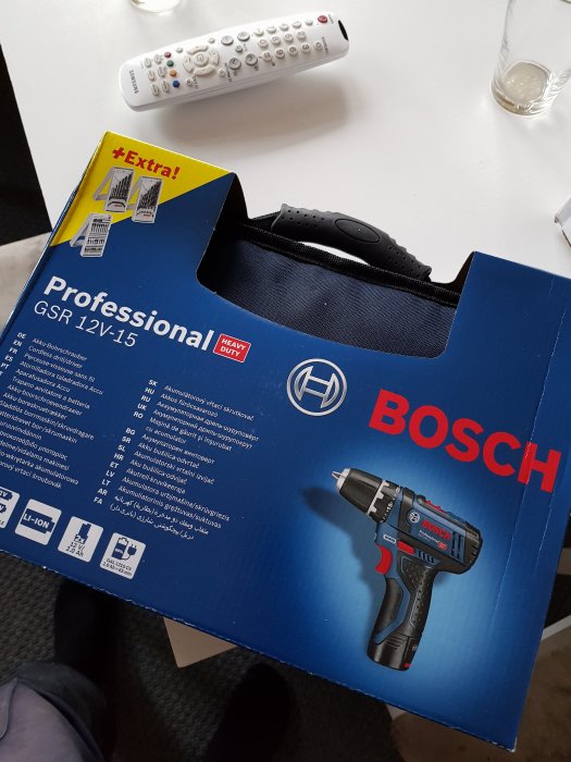 Bosch Professional GSR 12V-15 skruvdragare i förpackning med reklamtexter och fjärrkontroll i bakgrunden.