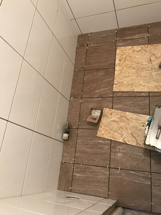 Ny lagd klinker i badrum med övergång till ofullständigt mosaikarbete och fix.