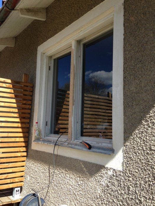 Nyskrapade och oljade fönsterkarmar vid renoverat hus med ställningar i bakgrunden.