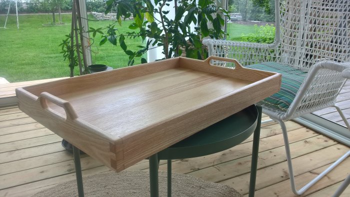 Handgjord träbricka i ask med Danish oil finish på ett bord på en veranda.