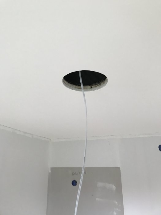 Öppen takgenomföring med sladd och oavslutad takinstallation i ett rum under renovering.